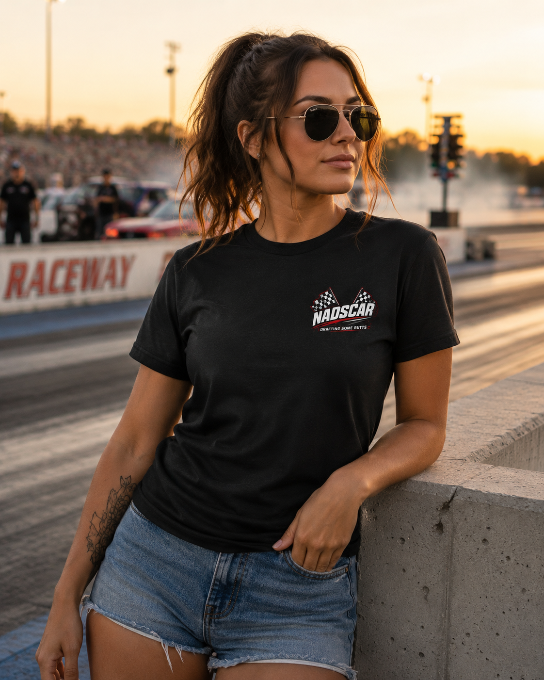Woman wearing a black t-shirt with a NADSCAR logo at a raceway.