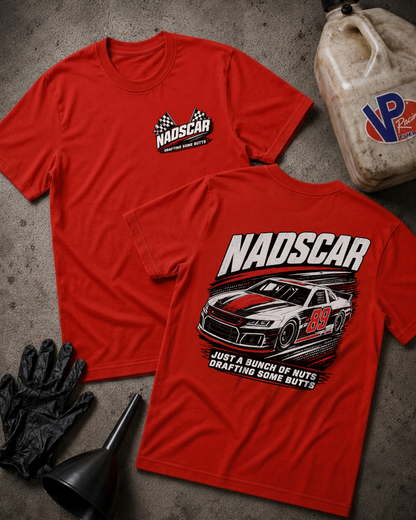 Two red short-sleeve T-shirts laid flat on a gray concrete-like surface, showing the front and back designs. The front has a small NADSCAR logo on the left chest, and the back has a large NADSCAR race car graphic with text.