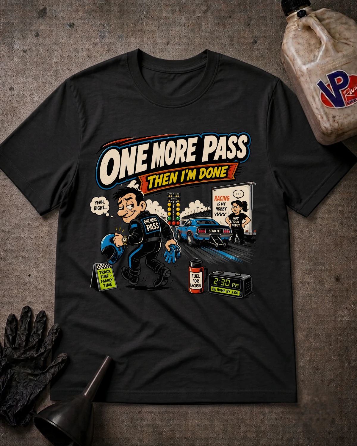 A black graphic t-shirt laid flat on a textured gray background with automotive-themed props including a plastic jug, gloves, and funnel. The shirt features a cartoon illustration of a police officer with a broken headlight, a blue race car, and the text 'ONE MORE PASS THEN I'M DONE'.