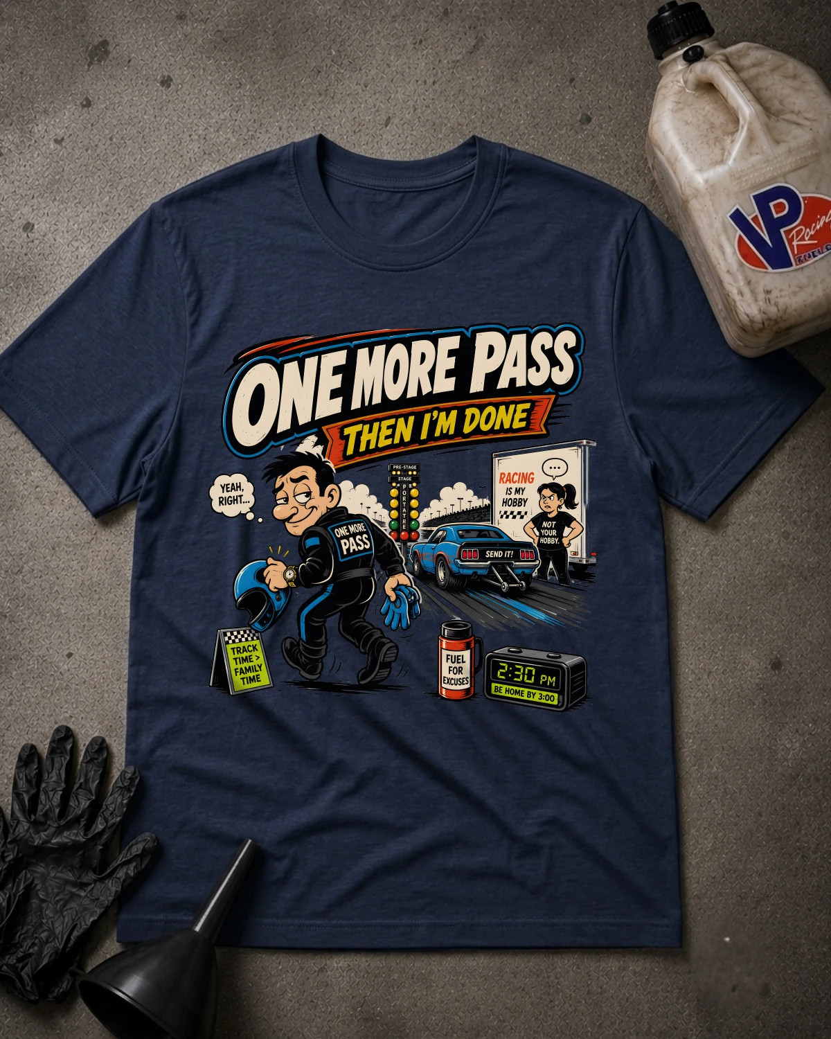 A navy blue graphic t-shirt laid flat on a textured gray surface, surrounded by racing-themed props including a black funnel, black gloves, and a plastic jug with a VP logo. The t-shirt features a colorful cartoon graphic with the text 'ONE MORE PASS THEN I'M DONE' and a race scene.