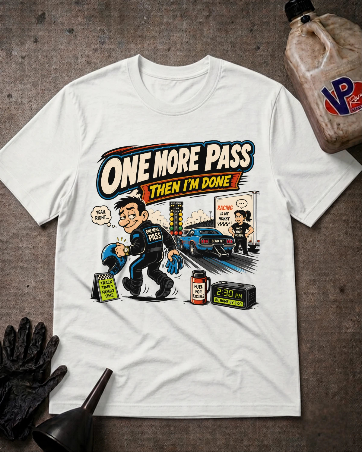 A white graphic t-shirt laid flat on a textured gray surface, featuring a cartoon illustration of a police officer taking a test with the text 'ONE MORE PASS THEN I'M DONE'. A black oil can, black gloves, and a funnel are arranged around the shirt as props.