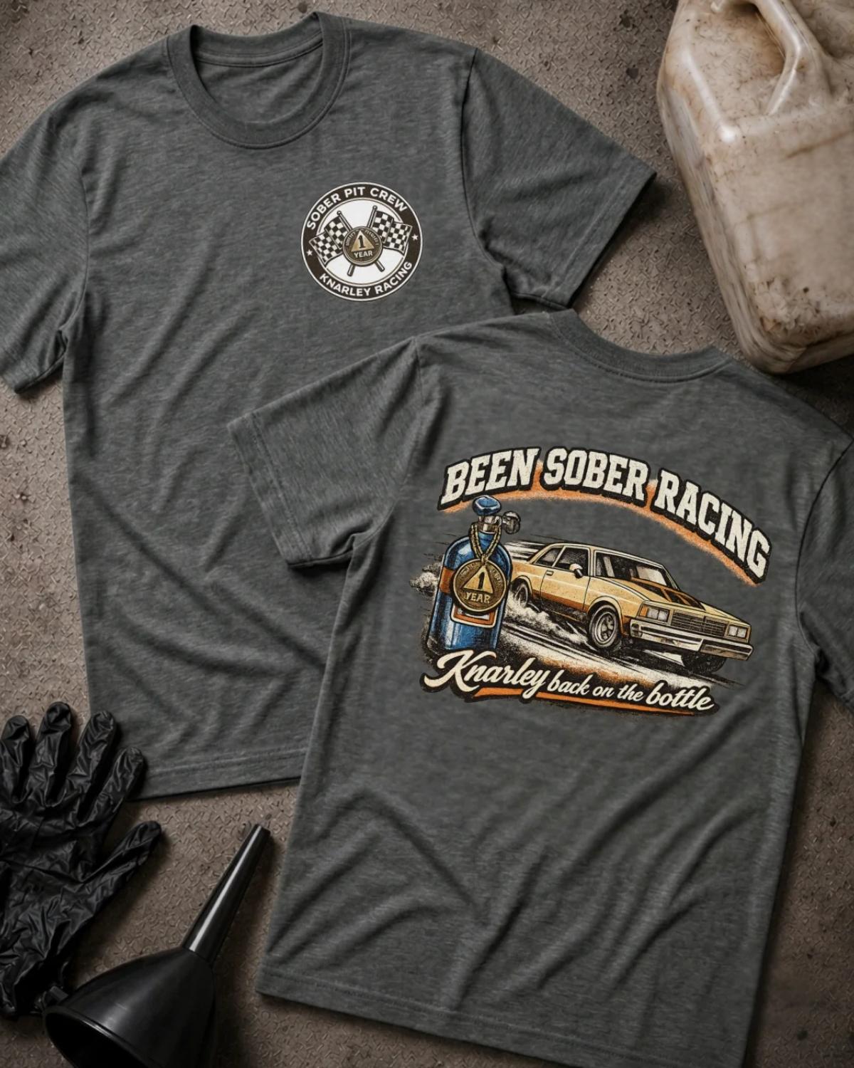 Front and back of dark grey heather Been Sober Racing T-shirt with a Sober Pit Crew chest emblem and gold drag car beside a blue nitrous bottle, reading “Knarley Back on the Bottle.”