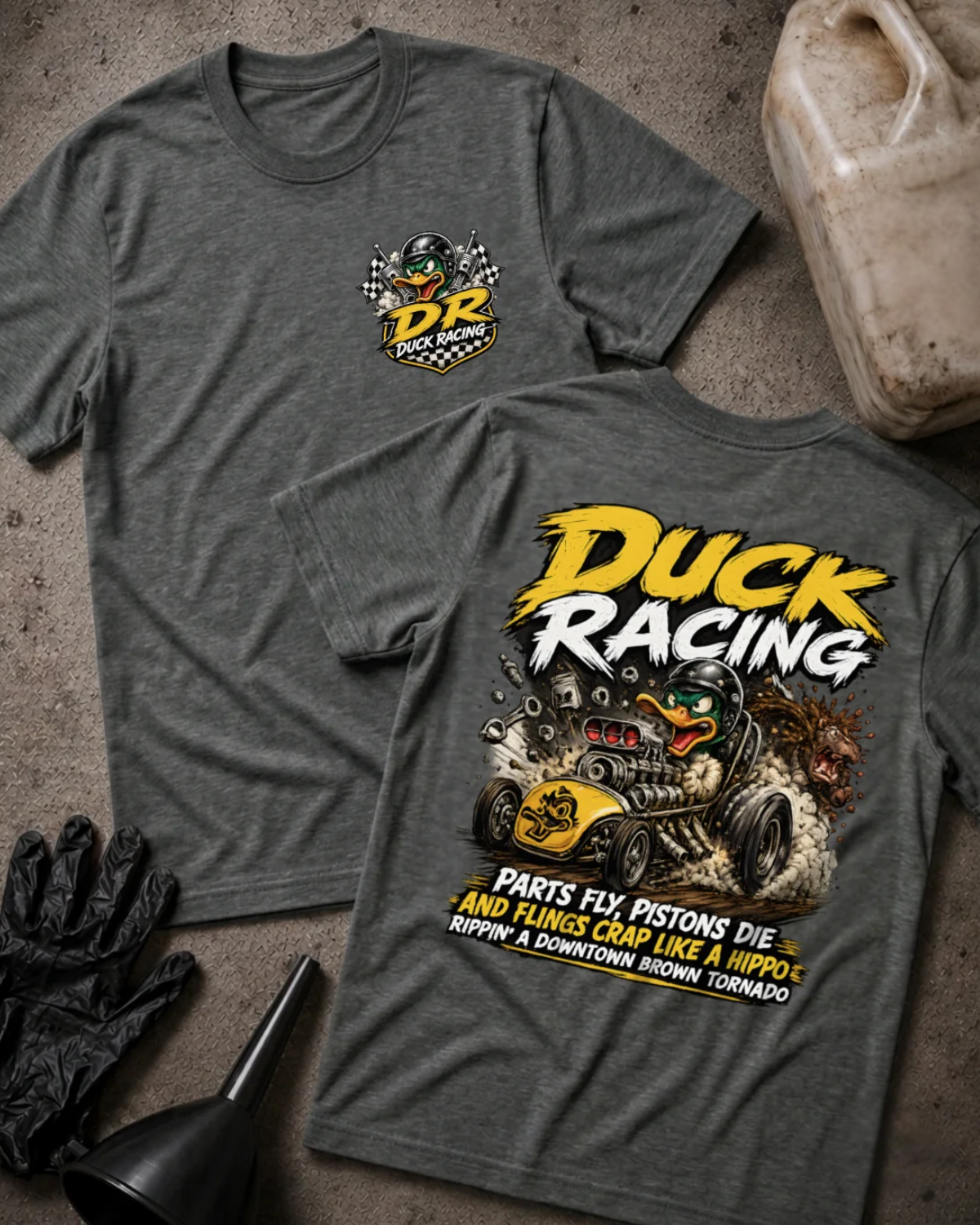 Front and back of dark grey heather Duck Racing T-shirt with a checkered-flag chest emblem and helmeted cartoon duck driving a yellow hot rod amid smoke and flying engine parts.