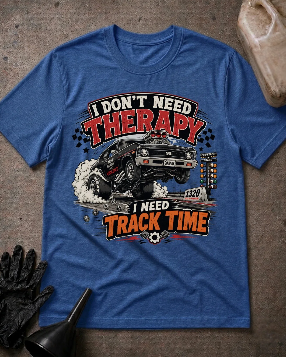 Front of heather true royal blue T-shirt with a black drag car lifting its front wheels beside a starting tree, reading “I Don’t Need Therapy, I Need Track Time.”