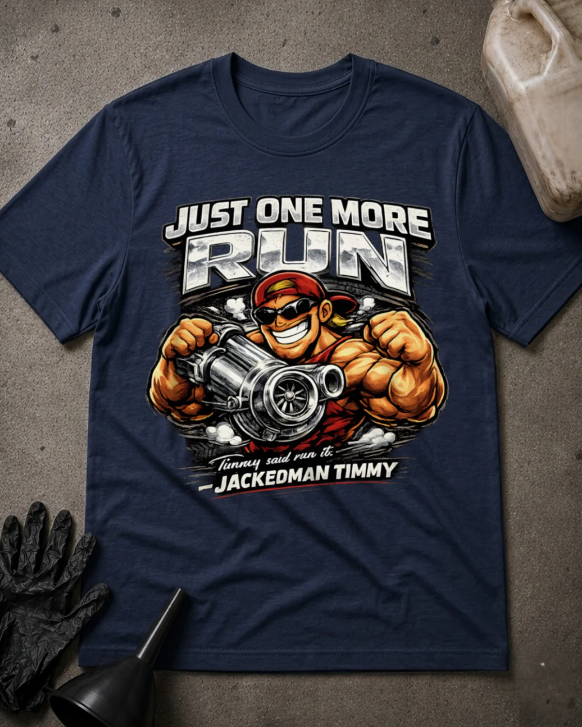 Front of navy T-shirt with muscular cartoon Jackedman Timmy in sunglasses and a red cap holding a turbocharger beneath “Just One More Run.”