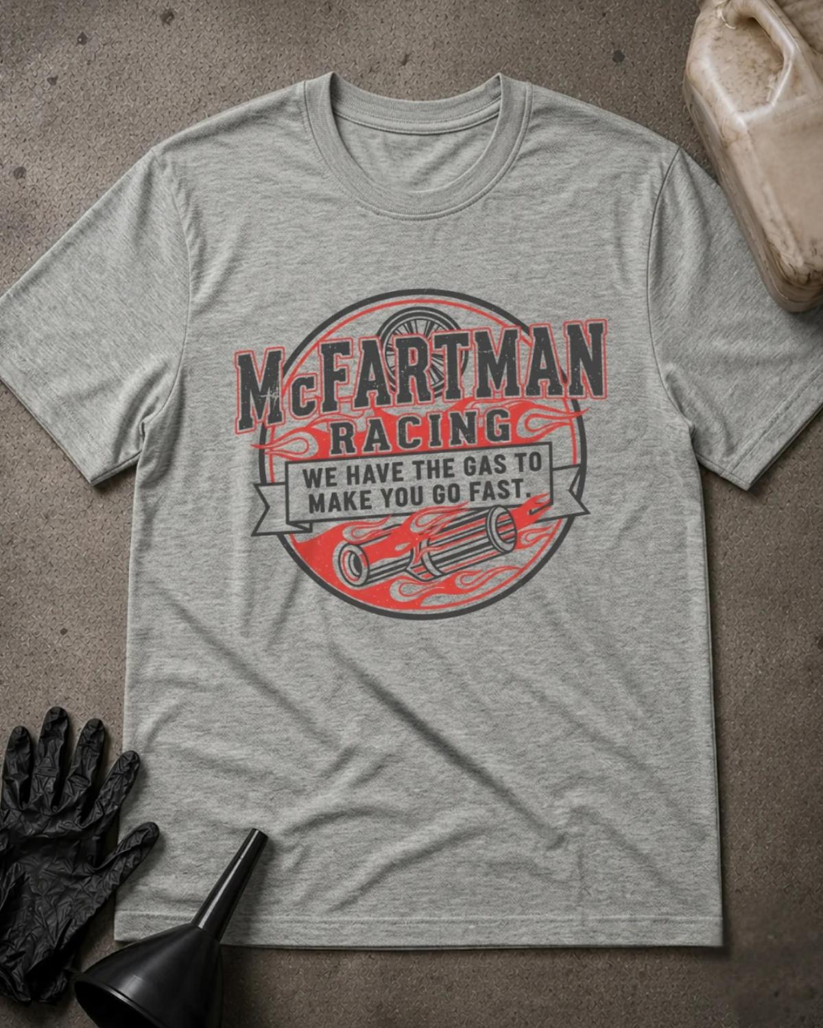 Athletic Heather gray McFartman Racing T-shirt featuring a circular emblem with red flames, exhaust pipes, a wheel, and the slogan “We have the gas to make you go fast.”