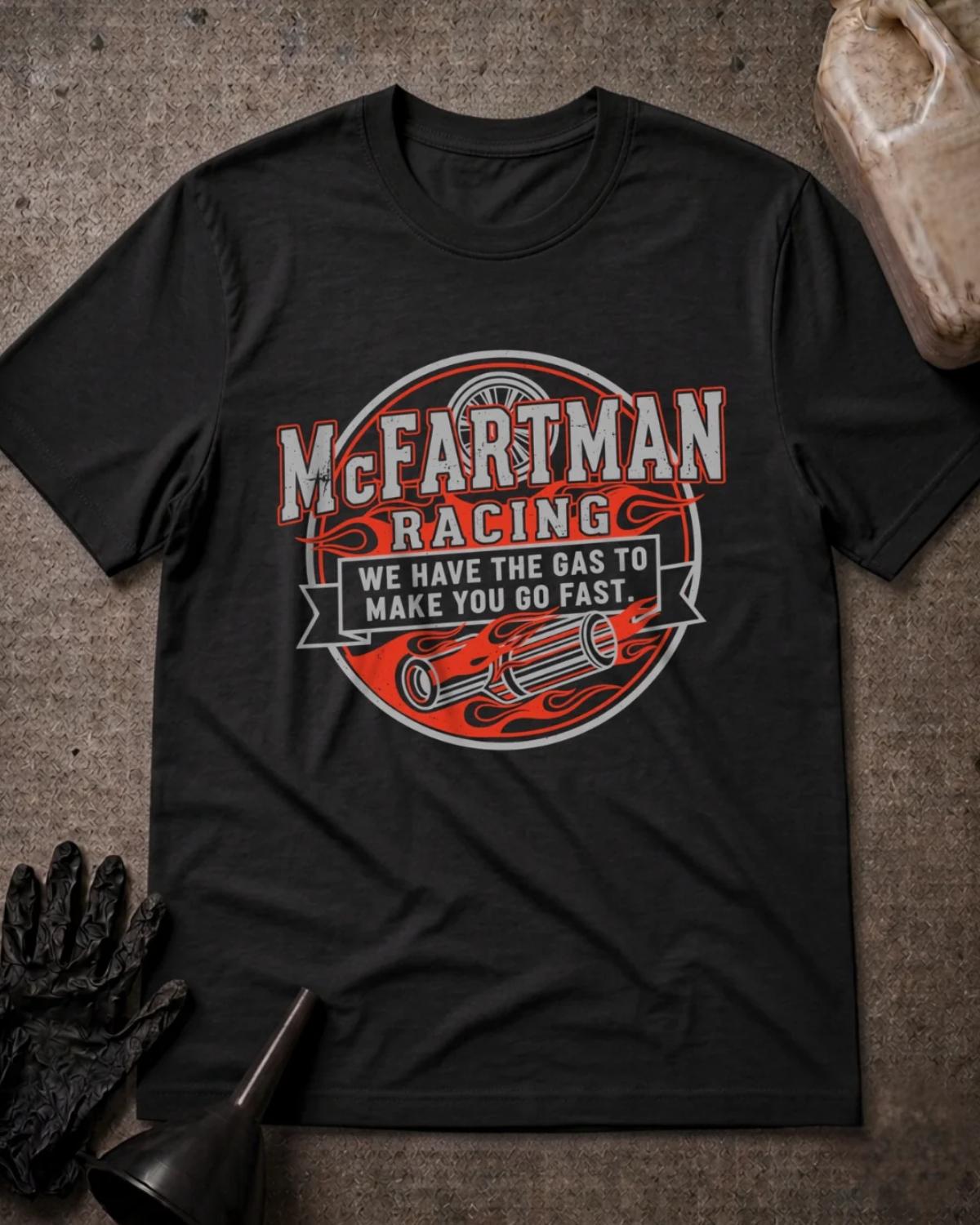 Black McFartman Racing T-shirt featuring a circular emblem with red flames, exhaust pipes, a wheel, and the slogan “We have the gas to make you go fast.”