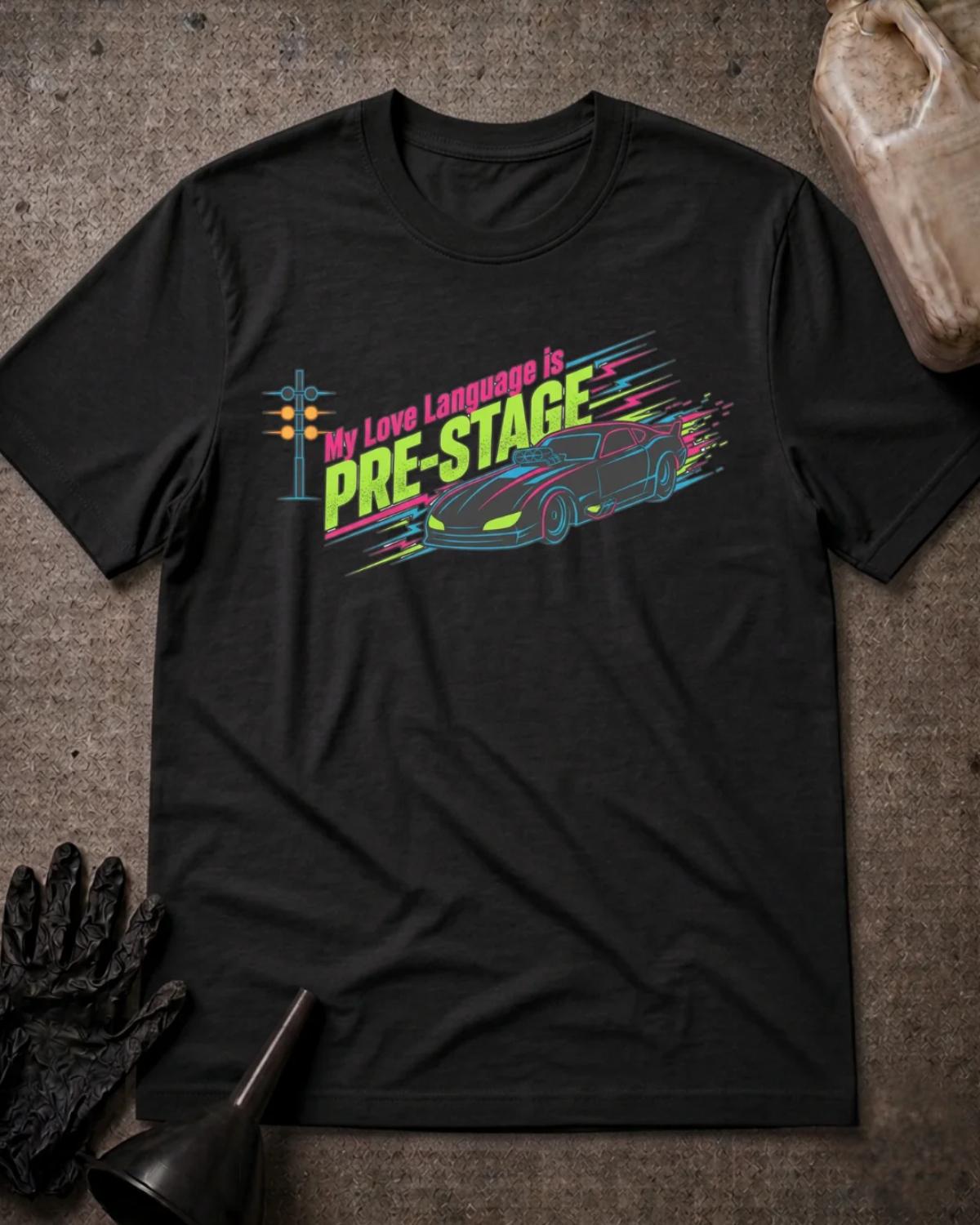 Black drag racing T-shirt featuring neon pink and lime “My love language is pre-stage” lettering, a sports car, a starting light, and colorful speed lines.
