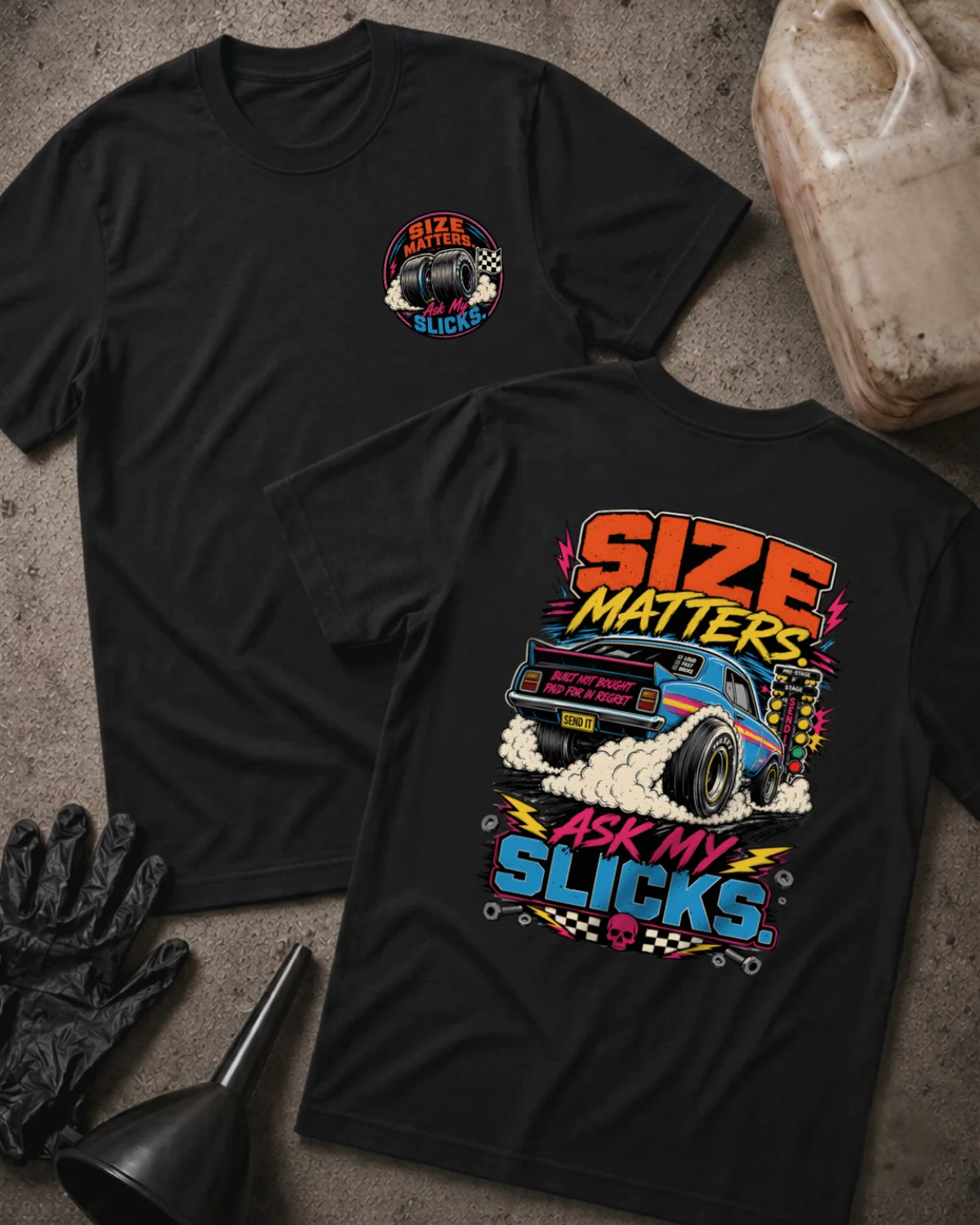 Front and back of black “Size Matters, Ask My Slicks” T-shirt with a small tire chest emblem and blue drag car with oversized rear slicks and tire smoke on the back.