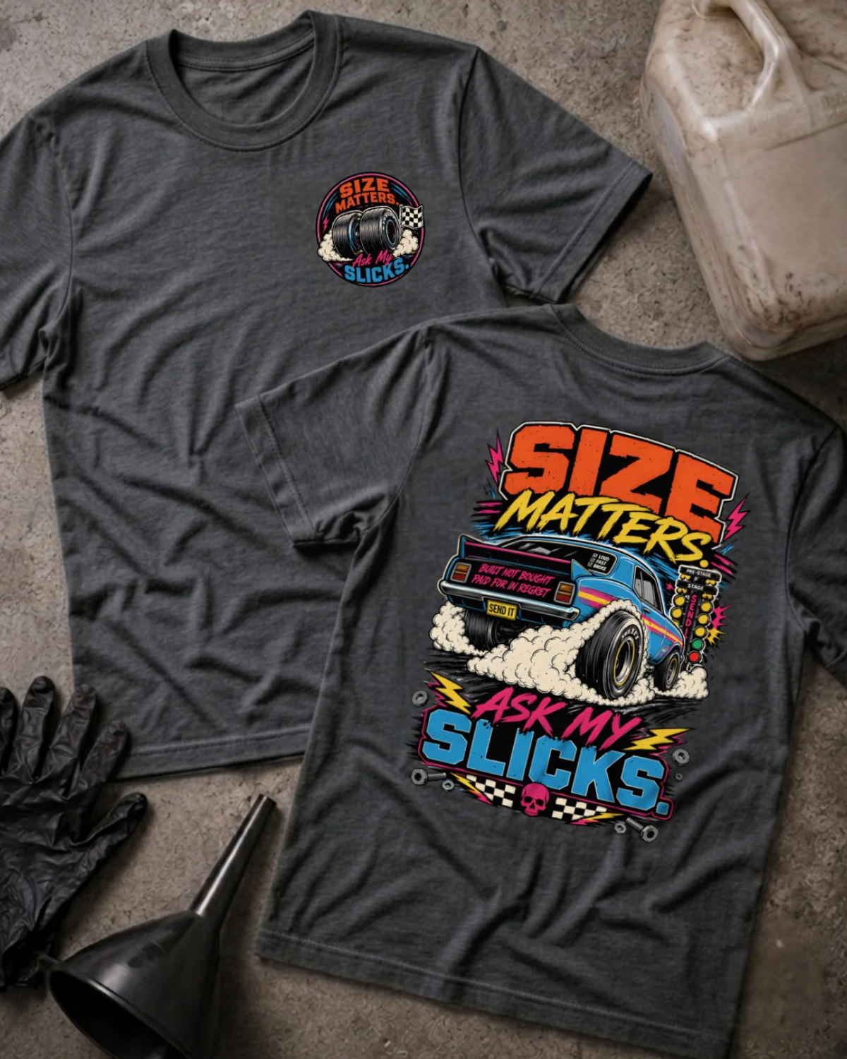 Front and back of dark grey heather “Size Matters, Ask My Slicks” T-shirt with a small tire chest emblem and blue drag car with oversized rear slicks and tire smoke on the back.