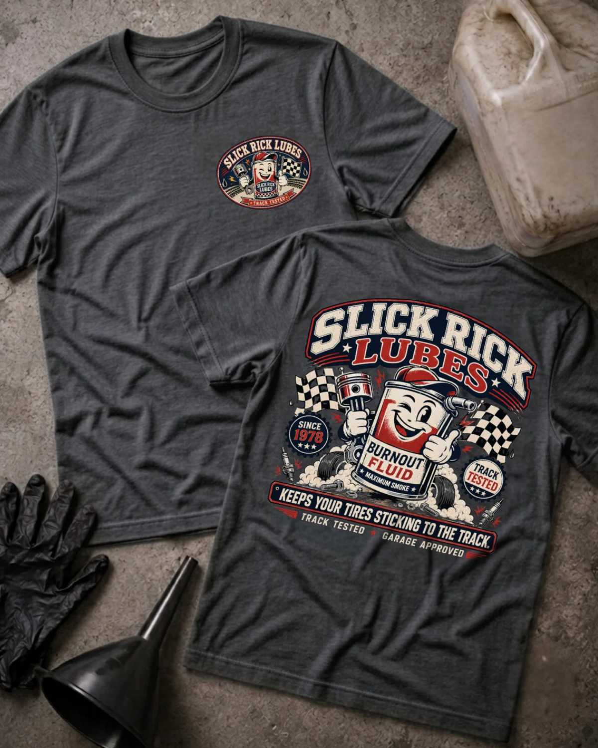Front and back of dark grey heather Slick Rick Lubes T-shirt with a chest logo and cartoon “Burnout Fluid” can holding an engine piston amid tires, smoke and checkered flags.