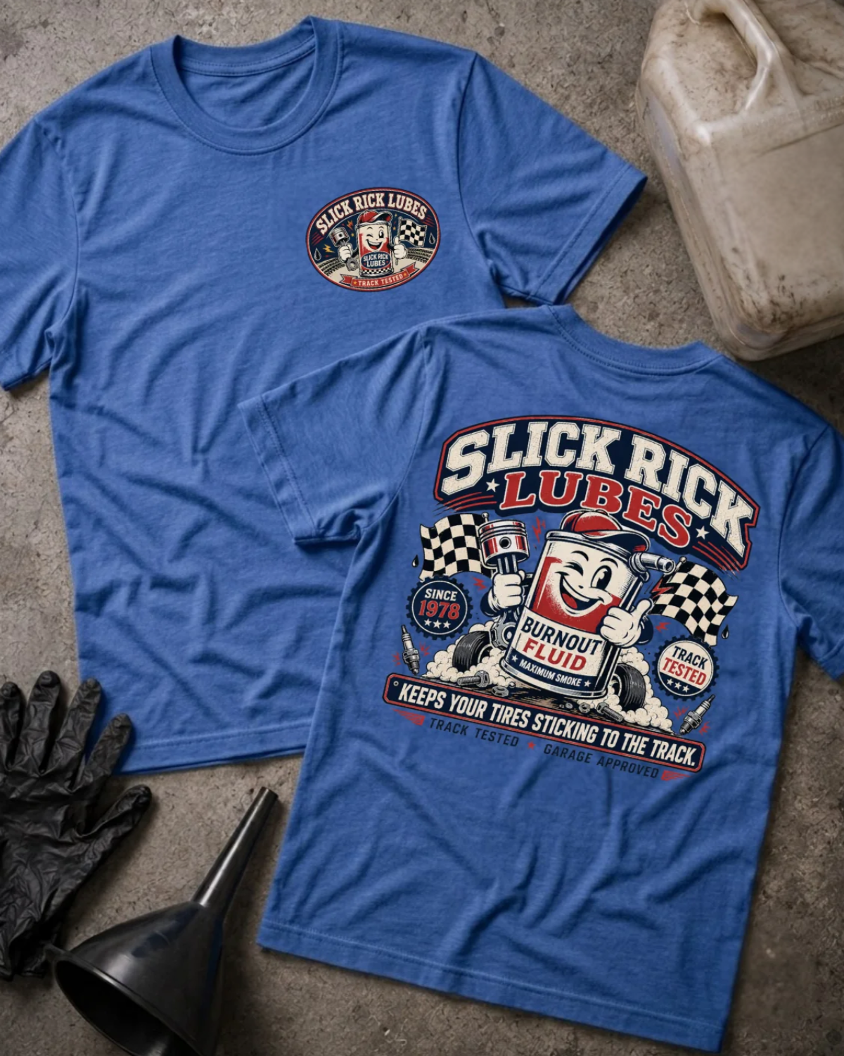 Front and back of heather true royal blue Slick Rick Lubes T-shirt with a chest logo and cartoon “Burnout Fluid” can holding an engine piston amid tires, smoke and checkered flags.