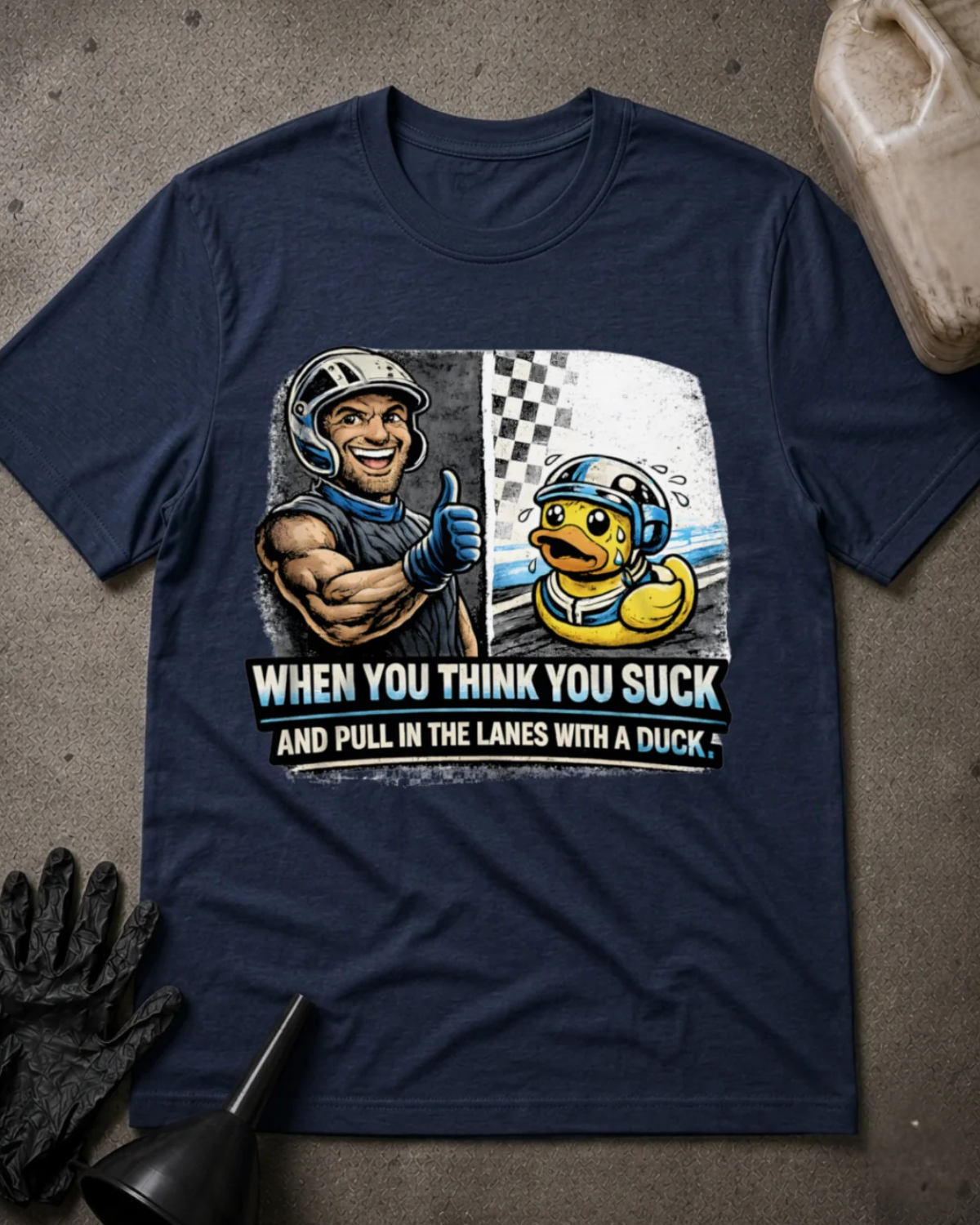 Front of navy T-shirt with a smiling racer giving a thumbs-up beside a nervous helmeted duck, reading “When You Think You Suck and Pull in the Lanes with a Duck.”