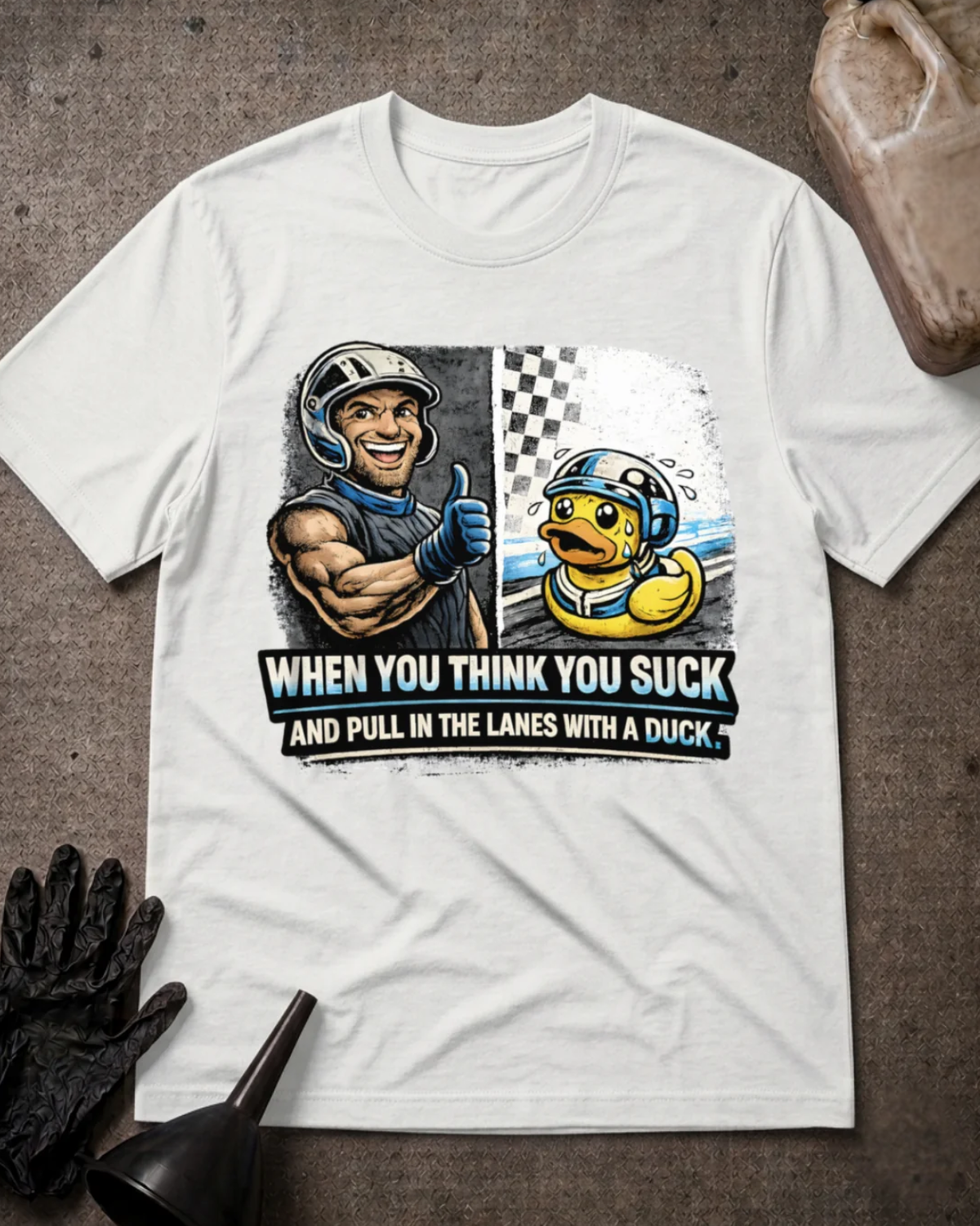 Front of white T-shirt with a smiling racer giving a thumbs-up beside a nervous helmeted duck, reading “When You Think You Suck and Pull in the Lanes with a Duck.”