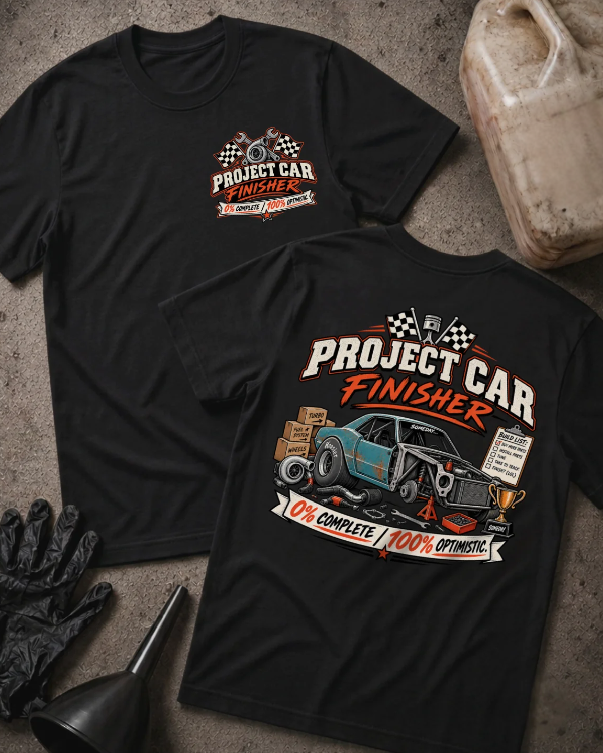 Front and back of Project Car Finisher black T-shirt with chest logo, unfinished teal car surrounded by parts and tools, and “0% complete / 100% optimistic” slogan.