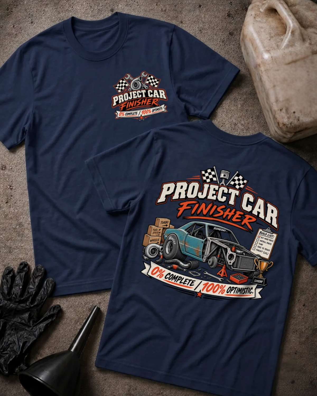 Front and back of Project Car Finisher navy T-shirt with chest logo, unfinished teal car surrounded by parts and tools, and “0% complete / 100% optimistic” slogan.