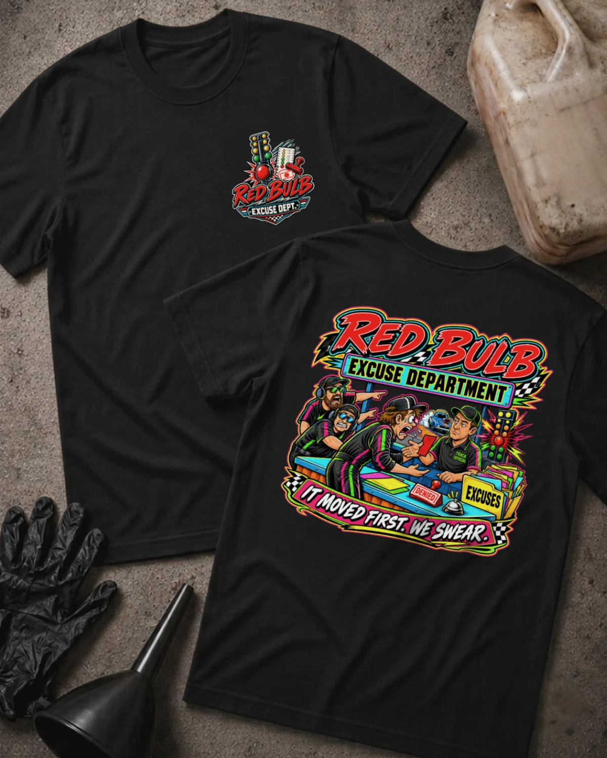 Front and back of Red Bulb Excuse Department black drag racing T-shirt with chest logo, racers arguing at an excuse desk beside a red starting light, and “It moved first. We swear.” slogan.