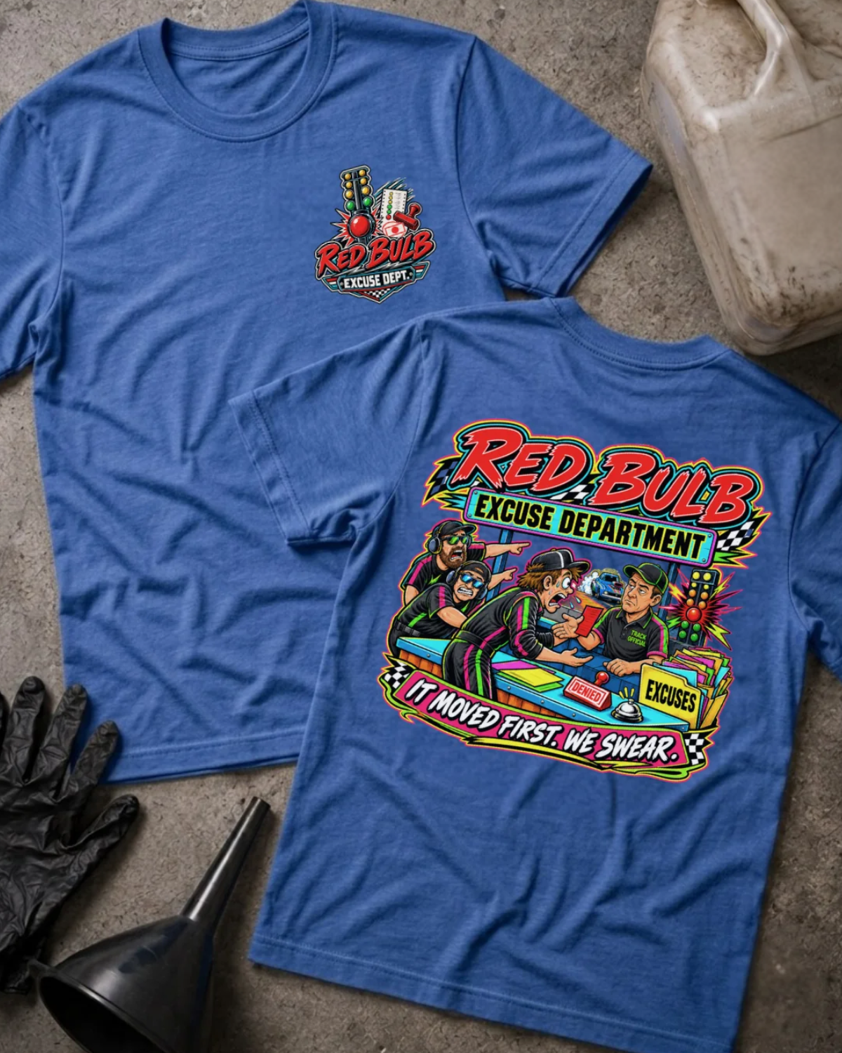 Front and back of Red Bulb Excuse Department heather true royal drag racing T-shirt with chest logo, racers arguing at an excuse desk beside a red starting light, and “It moved first. We swear.” slogan.