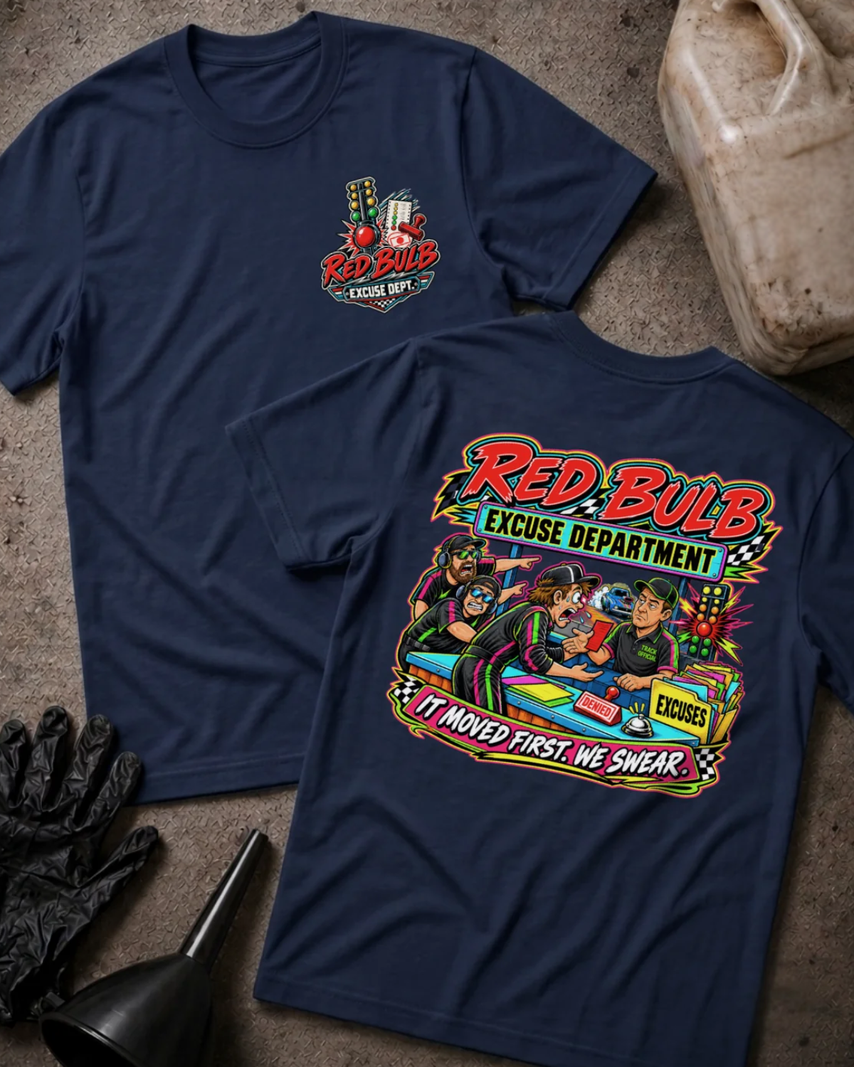 Front and back of Red Bulb Excuse Department navy drag racing T-shirt with chest logo, racers arguing at an excuse desk beside a red starting light, and “It moved first. We swear.” slogan.