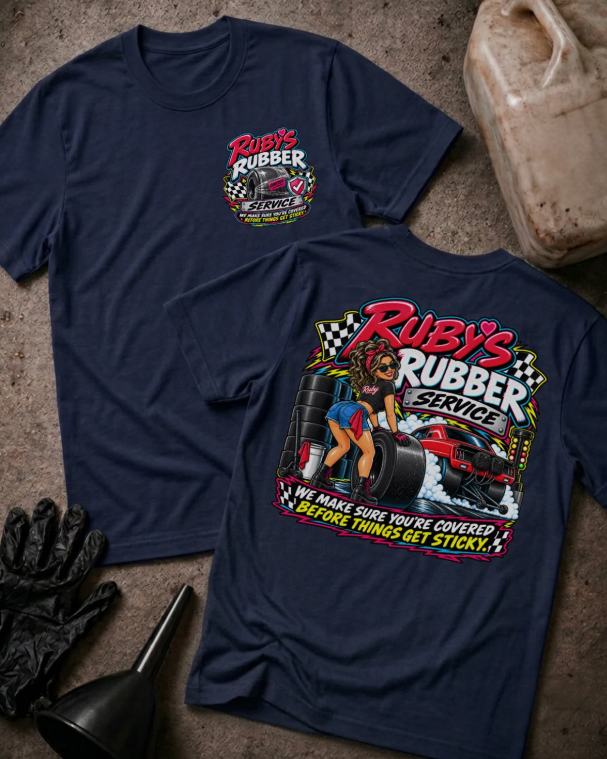 Front and back of Ruby’s Rubber Service navy T-shirt with chest logo, woman beside racing tires and a red drag car, and “We make sure you’re covered before things get sticky” slogan.