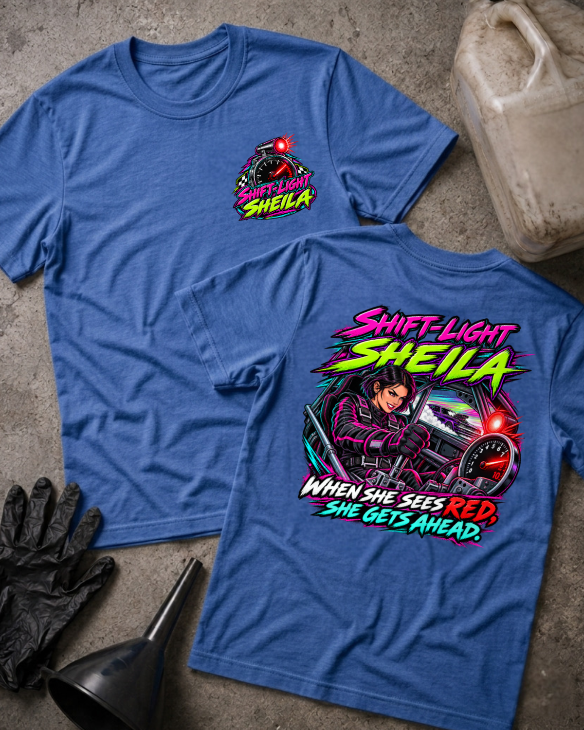 Heather true royal blue Shift-Light Sheila T-shirt, front and back: small chest tachometer emblem and neon woman driver graphic with red shift light and “When she sees red, she gets ahead.”