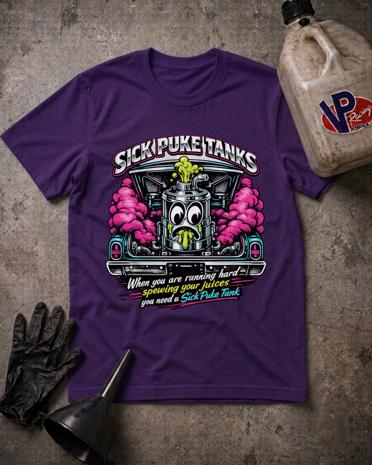 A purple graphic t-shirt laid flat on a textured gray surface, surrounded by black gloves, a metal funnel, and an oil jug. The t-shirt features a cartoon hot rod engine with pink smoke, the text 'SICK PUKE TANKS', and a humorous quote about running hard and needing a SICK Puke Tank.
