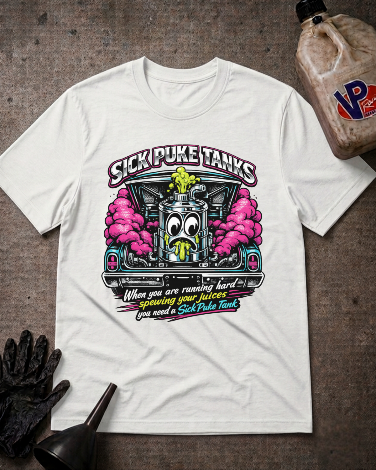 A white graphic t-shirt laid flat on a textured gray surface, featuring a cartoon fuel pump with pink clouds and the text 'SICK PUKE TANKS' and 'When you are running hard you need a Sick Puke Tank'. A plastic jug, black gloves, and a funnel are styled around the shirt.