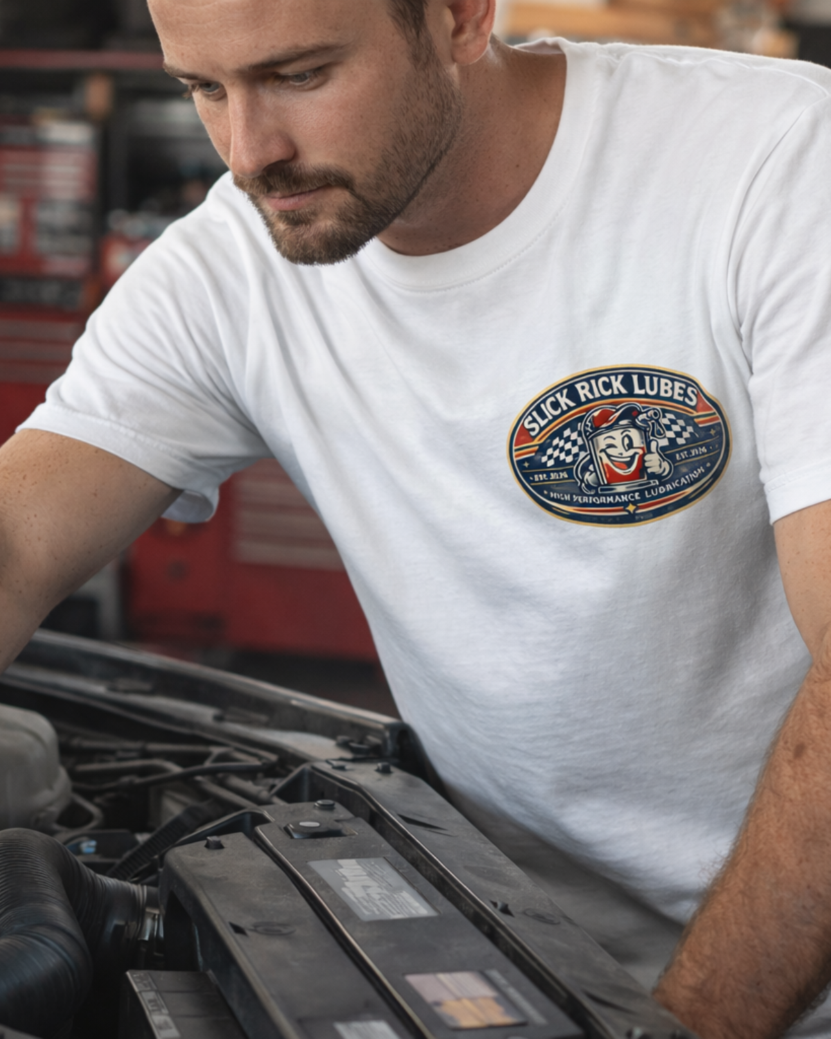 Man working on a car engine wearing a white t-shirt with a 'Slick Rick Lubes' logo.