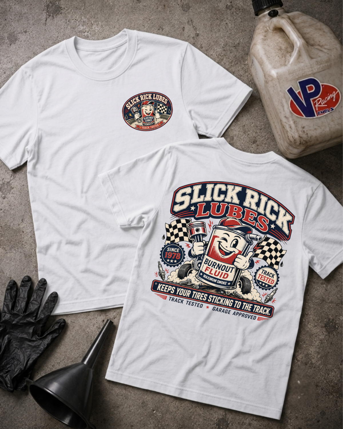 Two white Slick Rick Lubes Burnout Fluid t-shirts displayed flat on a gray concrete surface, with a black funnel, black gloves, and a VP Racing jug as props