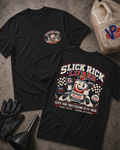 Two black graphic T-shirts laid flat on a textured gray surface, showing the front and back designs. The shirts feature a circular 'Slick Rick Lubes' logo on the front chest and a large retro-style 'Slick Rick Lubes' graphic on the back.