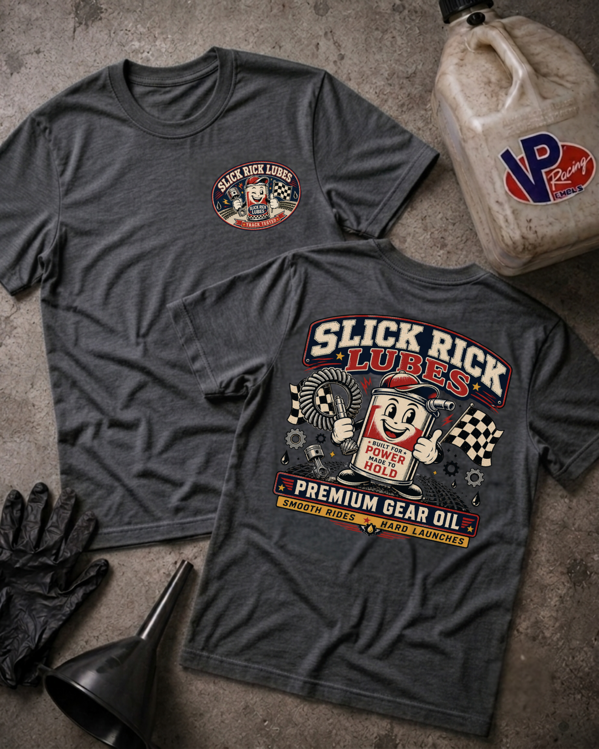 Two dark heather gray graphic T-shirts laid flat on a concrete floor, showing the front and back designs for 'Slick Rick Lubes'. A vintage VP Racing fuel jug, black gloves, and a black funnel are styled around the shirts.