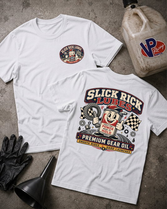 Two white graphic T-shirts laid flat on a gray concrete surface, with a black funnel, black gloves, and a VP Racing jug as styled props. The front shirt shows a small circular chest graphic reading 'Black Rick Lubes,' and the back shirt shows a large colorful 'Slick Rick Lubes' graphic with a cartoon character and text including 'Premium Gear Oil Smooth Rides Hard Launches.'
