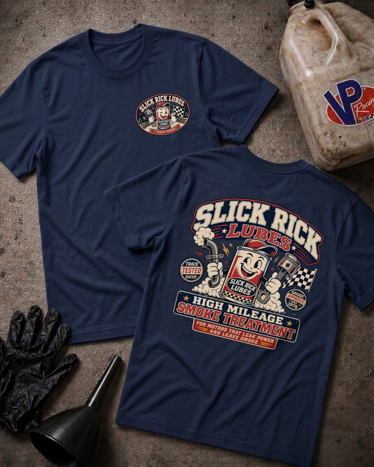 Two navy blue t-shirts displayed flat on a textured concrete surface, showing both the front and back designs for Slick Rick Lubes High Mileage Smoke Treatment. The front features a small circular logo on the left chest, while the back features a large, detailed graphic print.