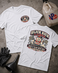 Two white graphic T-shirts laid flat on a gray concrete surface, with a black funnel, black gloves, and a VP Racing jug as props. The front shirt has a small circular chest graphic, and the back shirt has a large colorful 'Slick Rick Lubes' graphic with a cartoon character and 'Keep It Slick With Rick Nobody Likes A Dry Shaft' text.