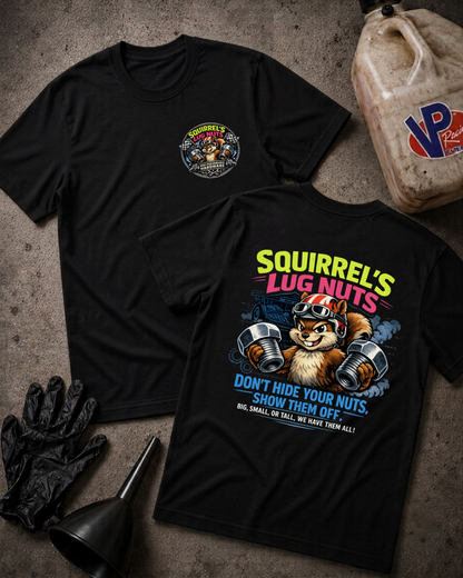 Two black graphic t-shirts laid flat on a textured gray surface, surrounded by black gloves, a funnel, and a plastic jug. The front shirt shows a small circular chest graphic, and the back shirt features a large colorful graphic of a squirrel lifting lug nuts with the text 'Squirrel's Lug Nuts'.