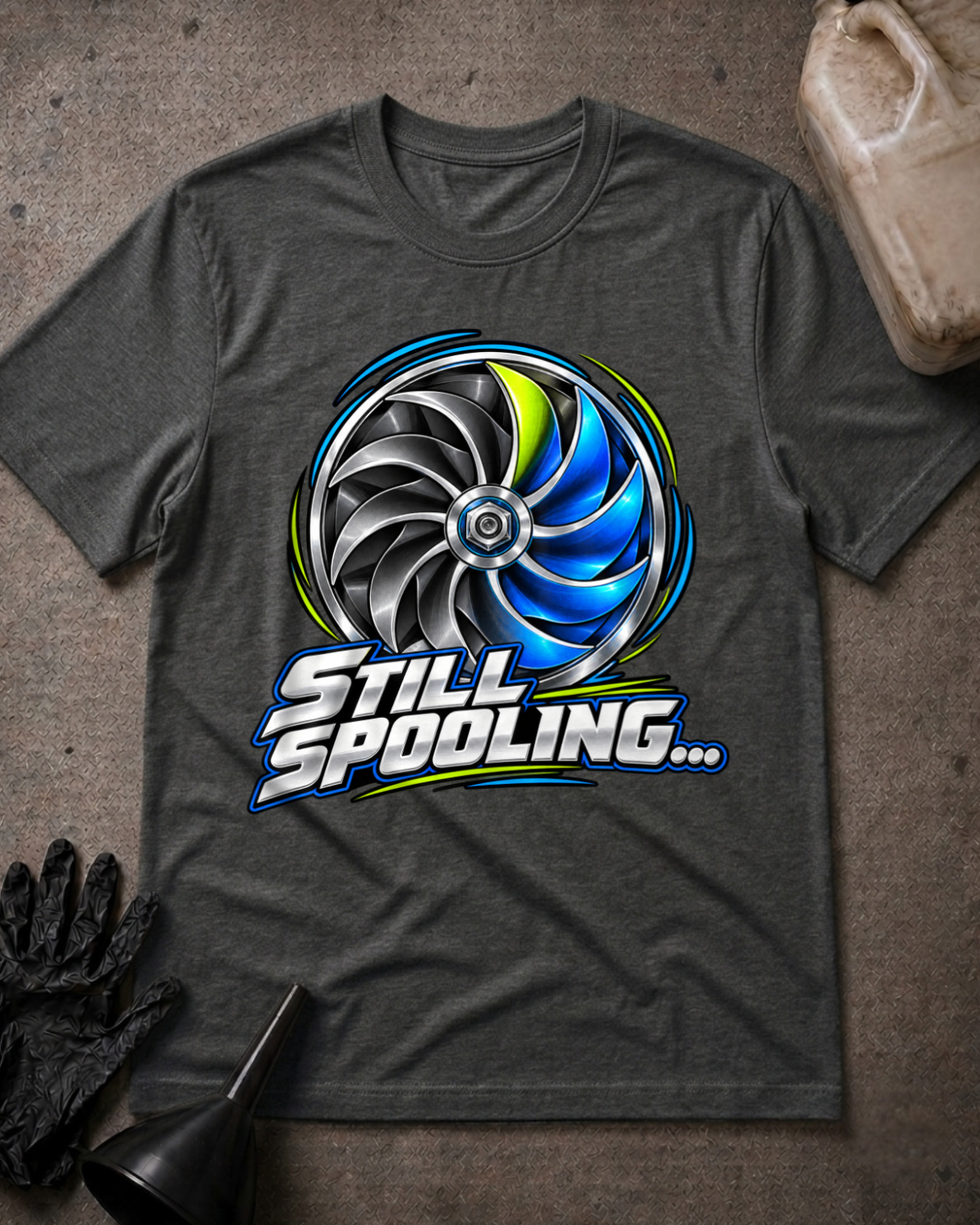 Dark grey heather T-shirt laid flat with a silver, black and blue turbo wheel graphic, lime accents and bold silver “Still Spooling…” lettering.