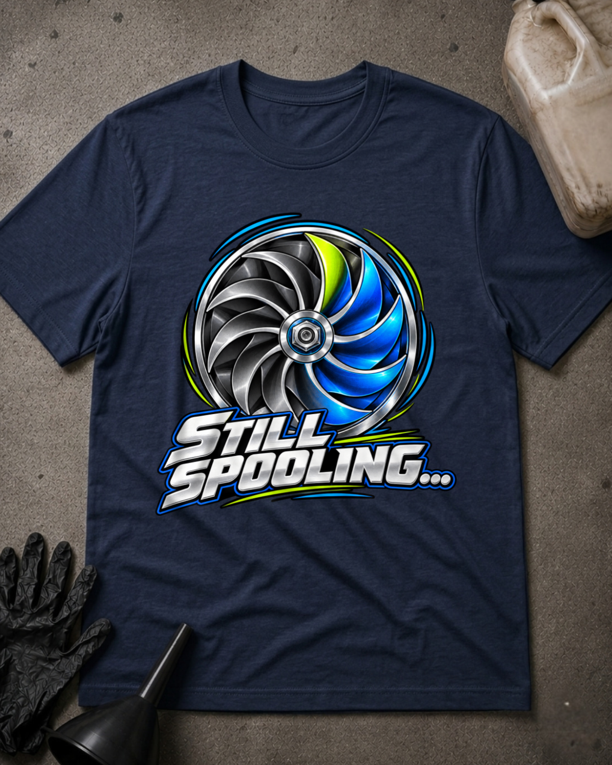 Navy T-shirt laid flat with a silver, black and blue turbo wheel graphic, lime accents and bold silver “Still Spooling…” lettering.