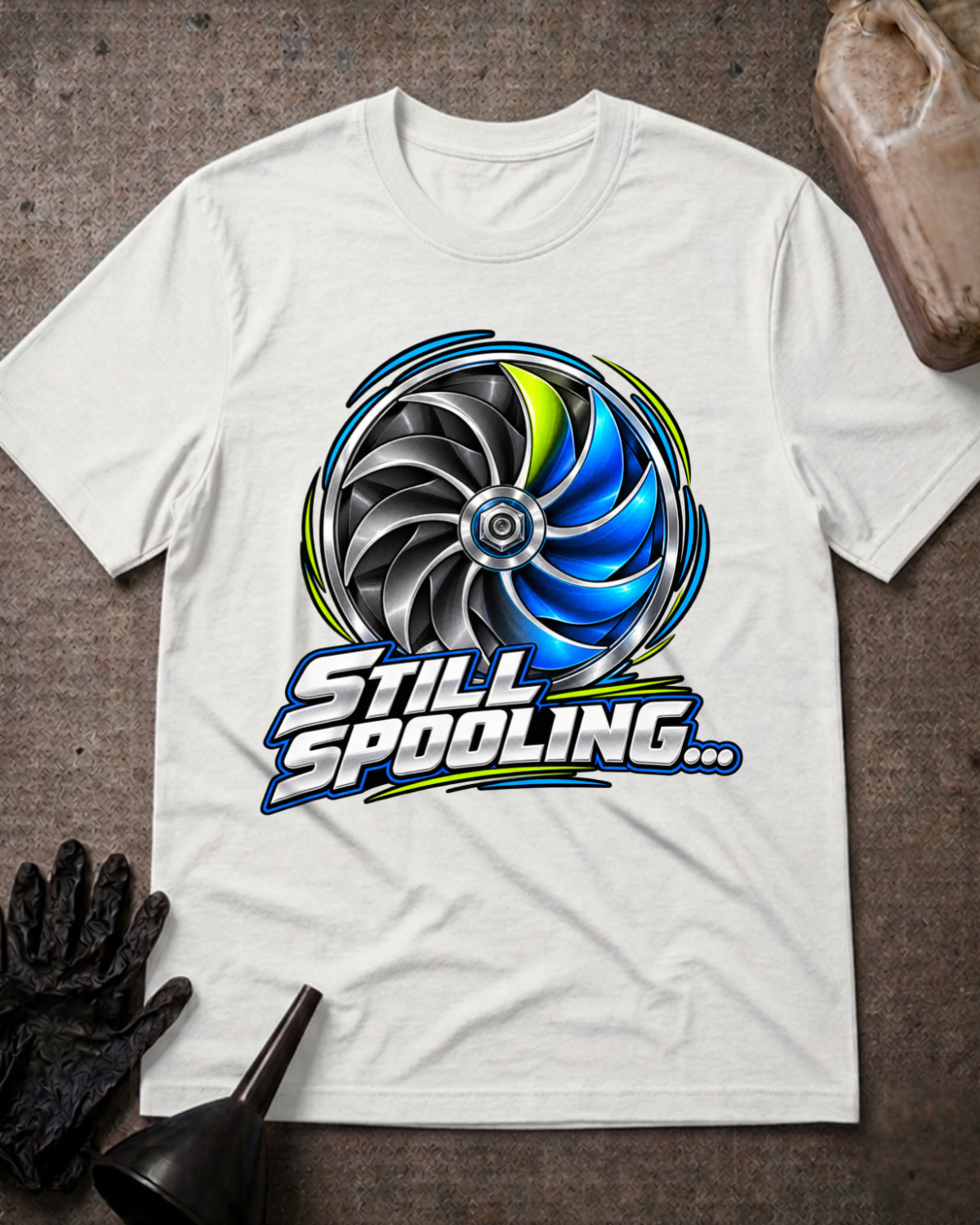 White T-shirt laid flat with a silver, black and blue turbo wheel graphic, lime accents and bold silver “Still Spooling…” lettering.