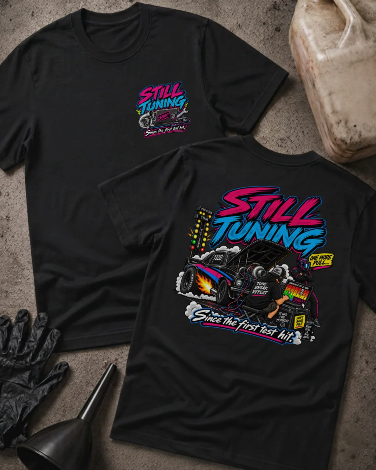 Front and back of Still Tuning black T-shirt with chest logo, mechanic using a laptop beside a drag car with open hood, and “Since the first test hit” slogan.