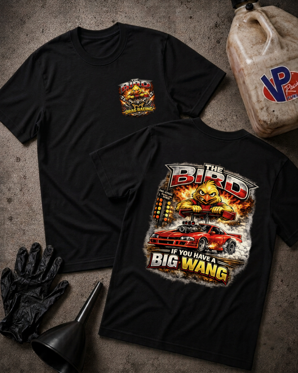 Two black graphic T-shirts laid flat on a textured gray surface, showing the front and back designs. The front has a small chest graphic, and the back has a large graphic featuring the text 'The Bird' and 'If You Have A Big Wang' with a red car and fiery illustration.