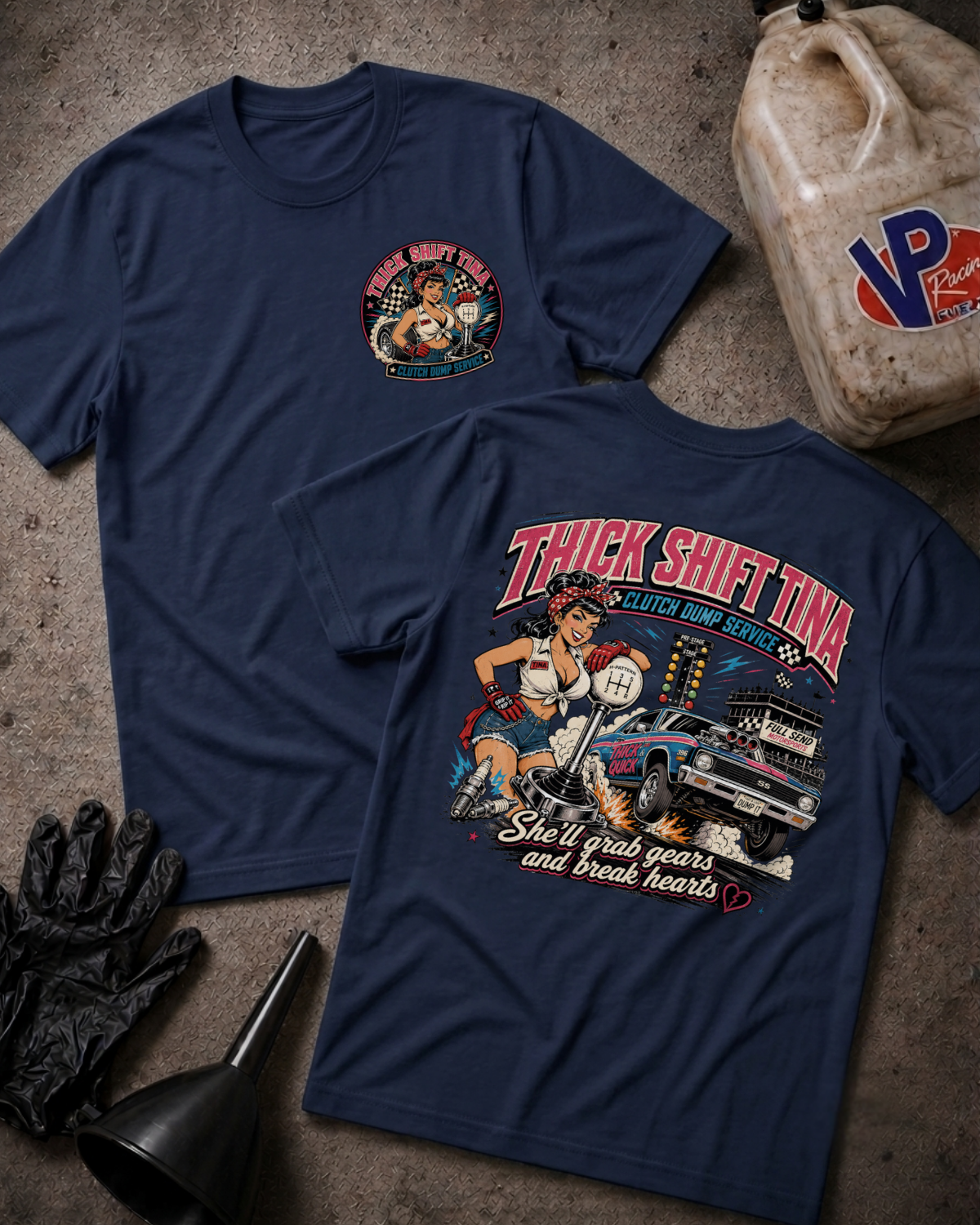 Two navy blue graphic t-shirts displayed flat on a textured concrete-like surface, with a vintage oil can, black gloves, and a funnel around them. The front shirt shows a small circular chest graphic, and the back shirt shows a large colorful graphic with the text 'THICK SHIFT TINA' and a pin-up style illustration.