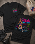 Two black graphic T-shirts laid flat on a textured concrete surface, with a gas can, black gloves, and a funnel nearby. The front shirt shows a small multicolor chest graphic reading 'Tina's Track Prep,' and the back shirt shows a large colorful graphic with the same text plus an illustrated woman and a race car.