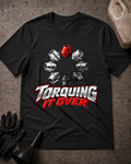 Black T-shirt laid flat with a ring of silver and black lug nuts, one red lug nut at the top, and bold silver and red “Torquing It Over” lettering.