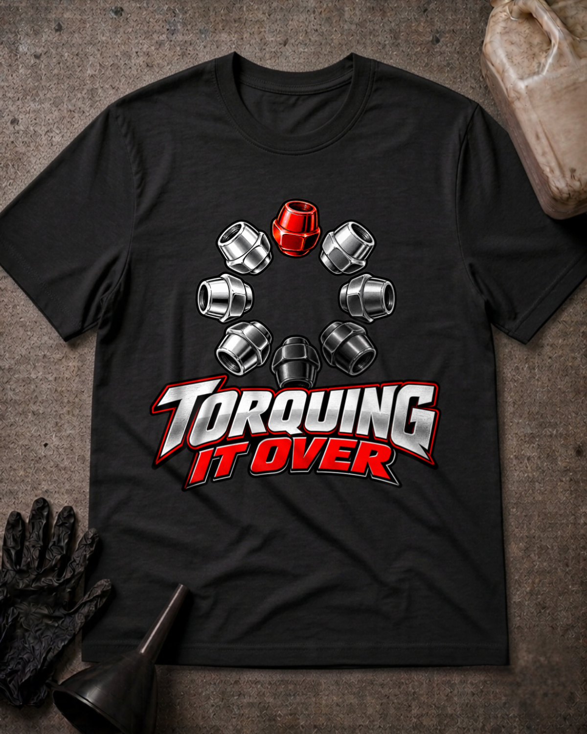 Black T-shirt laid flat with a ring of silver and black lug nuts, one red lug nut at the top, and bold silver and red “Torquing It Over” lettering.