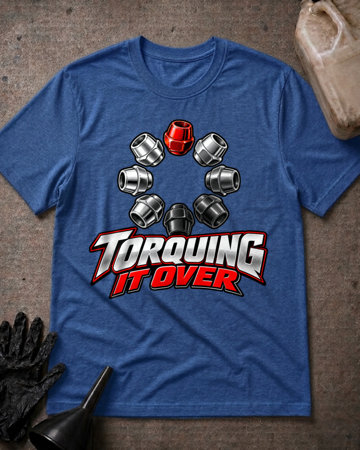 Heather true royal blue T-shirt laid flat with a ring of silver and black lug nuts, one red lug nut at the top, and bold silver and red “Torquing It Over” lettering.
