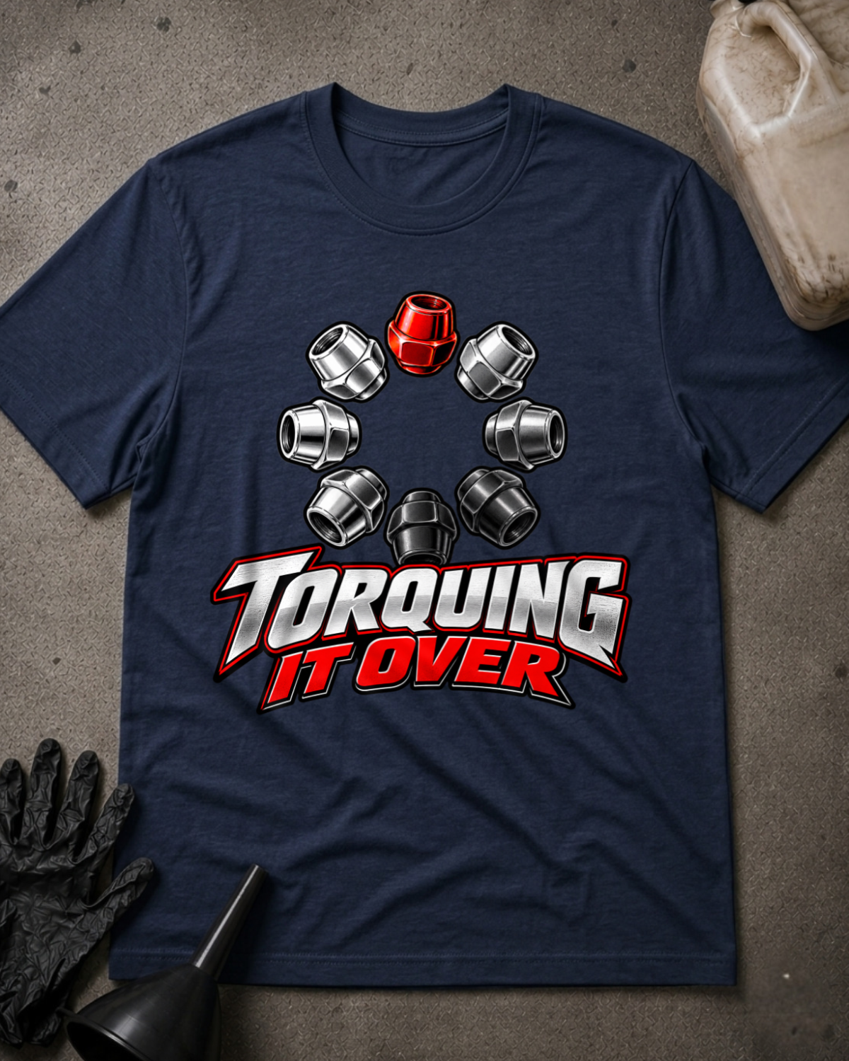 Navy T-shirt laid flat with a ring of silver and black lug nuts, one red lug nut at the top, and bold silver and red “Torquing It Over” lettering.