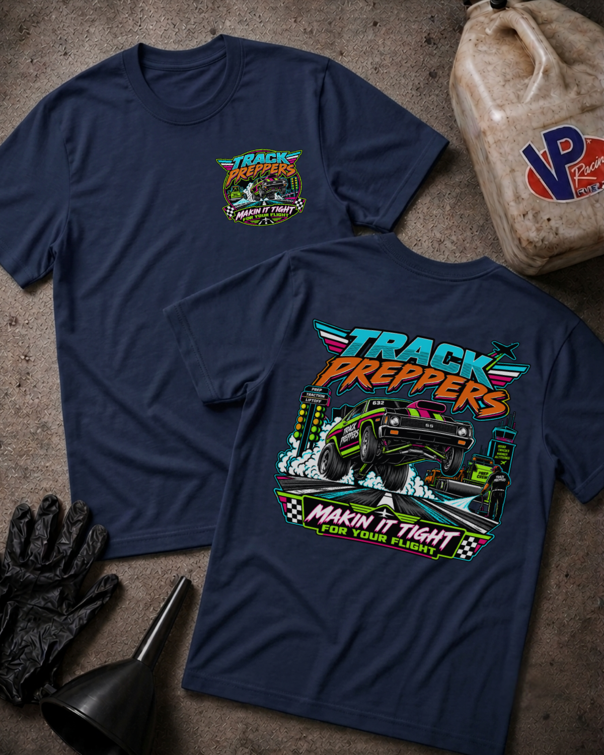 Two navy blue t-shirts displayed on a textured concrete surface, showing both the front and back graphics for 'Track Preppers Racing'. The shirts are styled with racing props including a plastic fuel jug, black gloves, and a funnel.