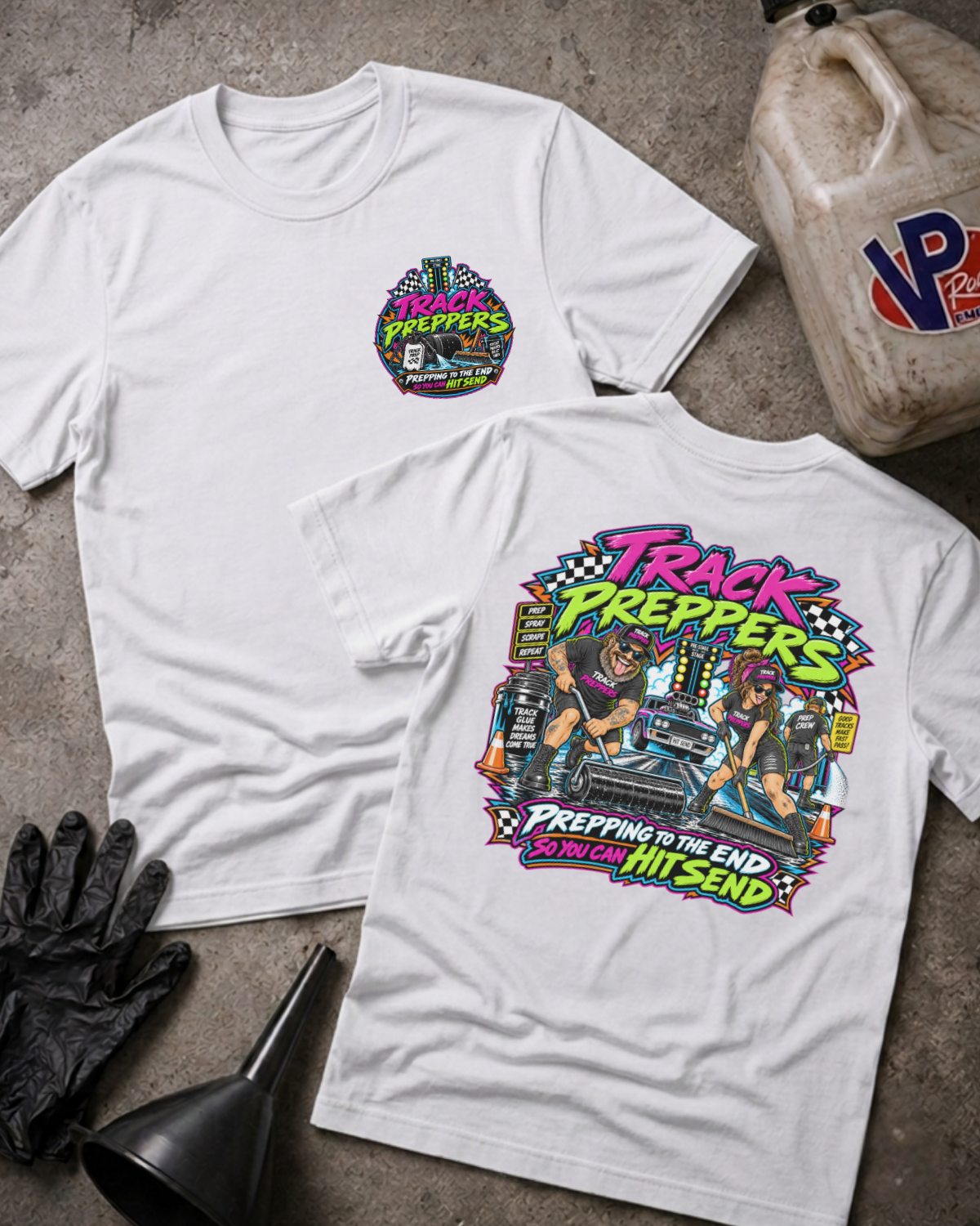 Two white graphic T-shirts laid flat on a concrete surface, showing the front and back designs. The front has a small circular multicolor chest graphic reading 'Track Preppers' with track prep tools.