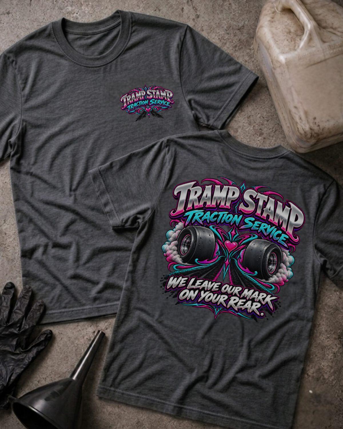 Dark grey heather Tramp Stamp Traction Service T-shirt, front and back views with a small chest logo and smoking racing slicks, pink and teal scrollwork, and “We leave our mark on your rear.”