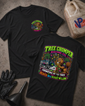 Two black 'TREE CHOMPER RACING CO.' graphic T-shirts laid flat on a textured gray surface, with racing-themed printed artwork and text. A black glove, funnel, and a plastic fuel can are placed around them as styled props.